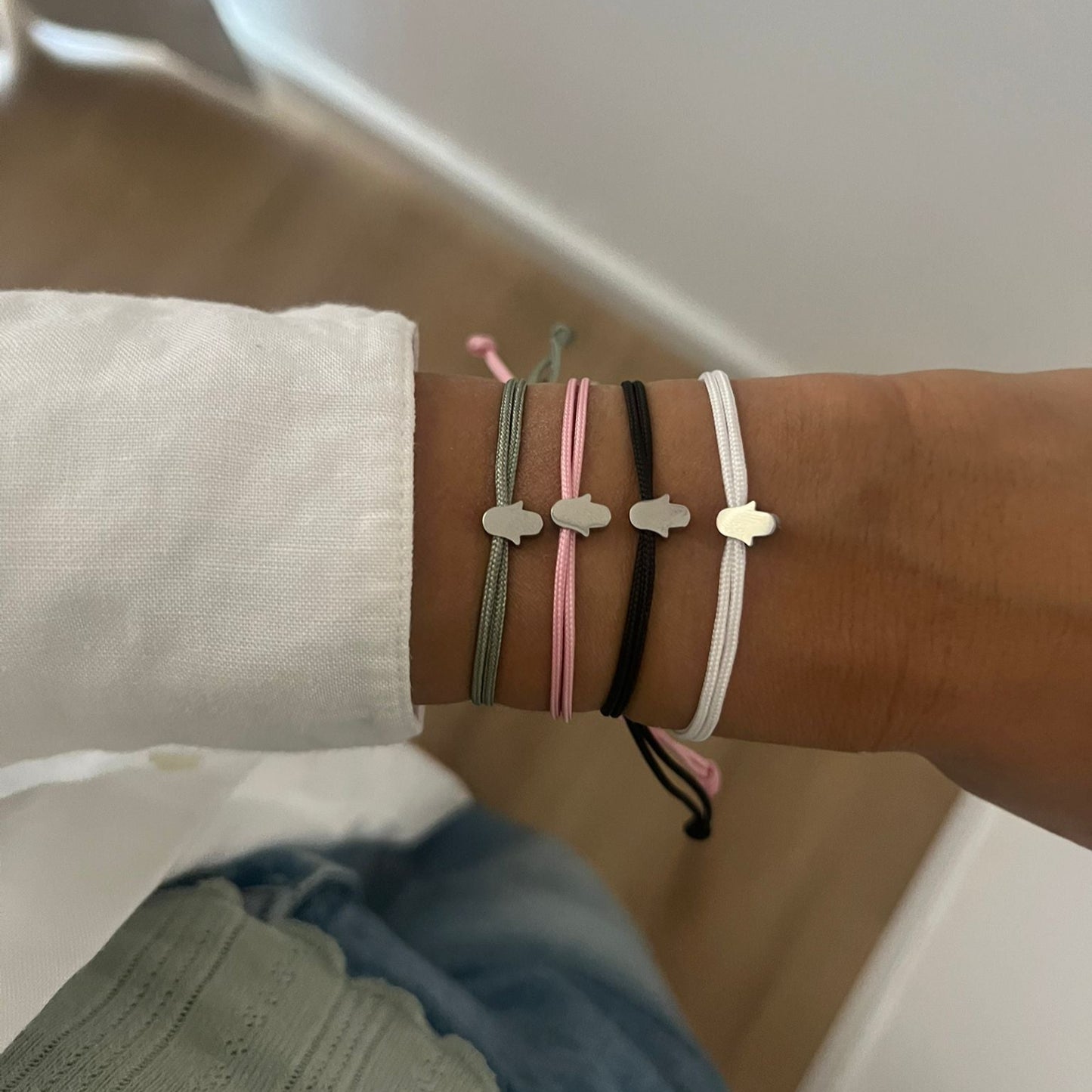 Wrist wearing multiple bracelets with a neutral background