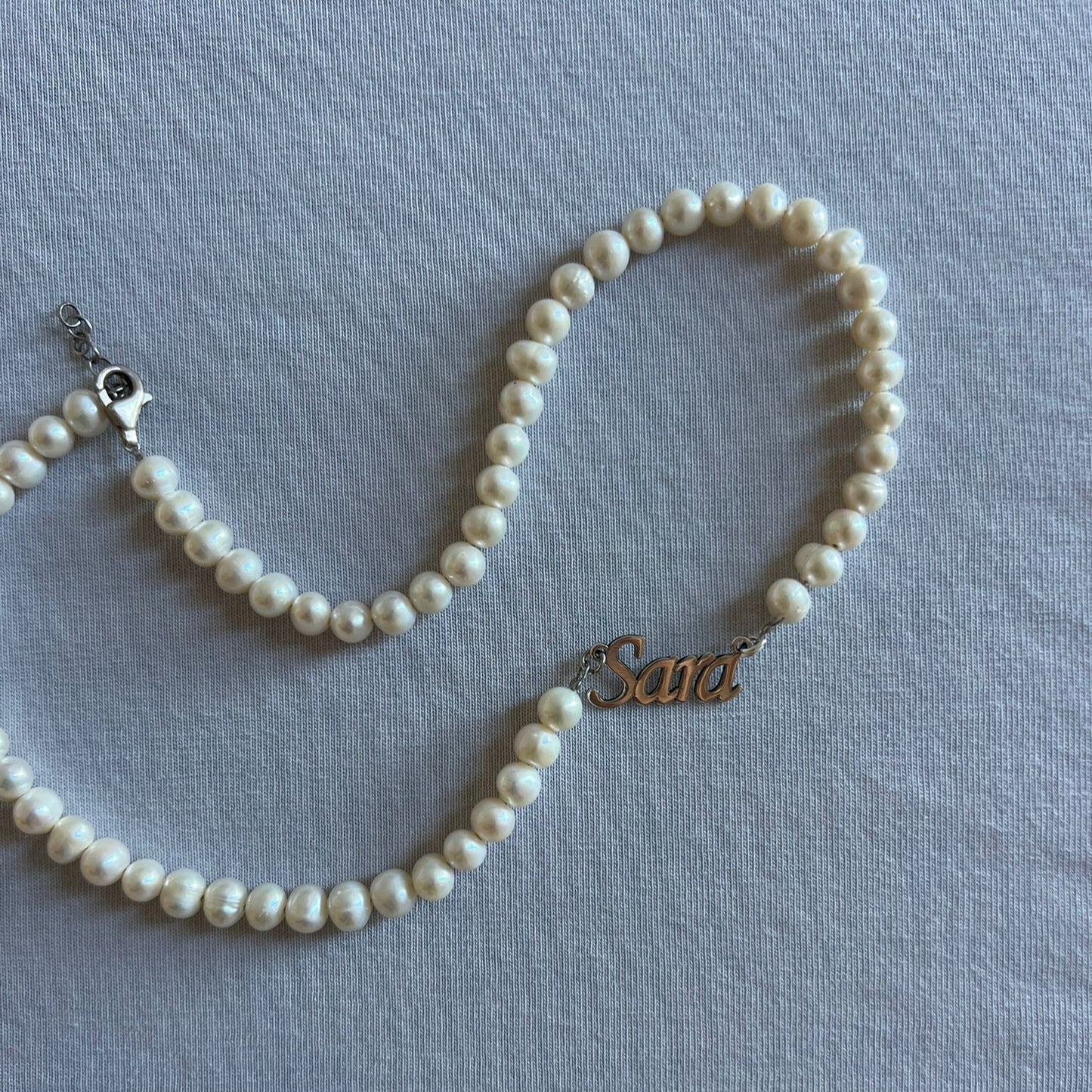 Pearl necklace with a gold clasp on a light blue background